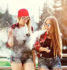 Two female adolescents vaping