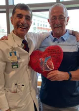 Pat holding his heart pillow with his physician after transplant